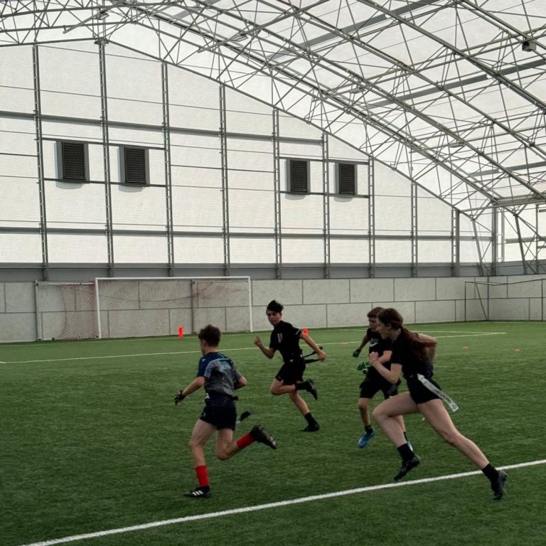 Fife All Stars flag football players chasing each other on indoor pitch.